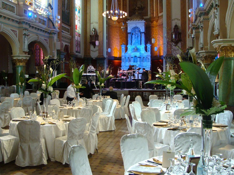 Salle de réception dans une ancienne église, tables rondes dressées en blanc